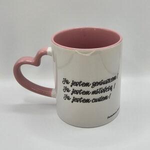 Kubek biały z różowym wnętrzem i uszkiem w kształcie serca z afirmacjami po obydwu stronach.